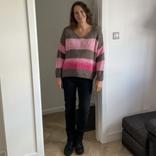 Load image into Gallery viewer, A woman stands in a doorway wearing a fuzzy knit sweater with horizontal stripes in taupe, brown, and pink, paired with black pants and black boots.