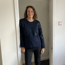 Load image into Gallery viewer, A woman stands in a doorway wearing a dark navy blue knit sweater with tonal floral embroidery and black pants.