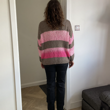 Load image into Gallery viewer, A person viewed from behind wearing a fuzzy knit sweater with horizontal stripes in taupe, light pink, and magenta, paired with dark jeans and black boots, standing in a doorway inside a home.
